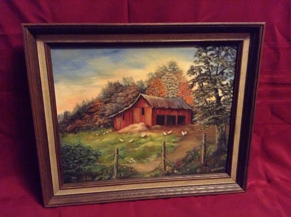 A framed painting of a red barn in a field