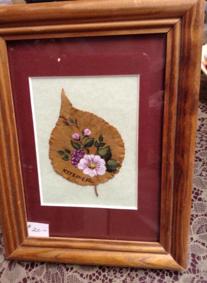 A framed picture of a leaf with flowers on it