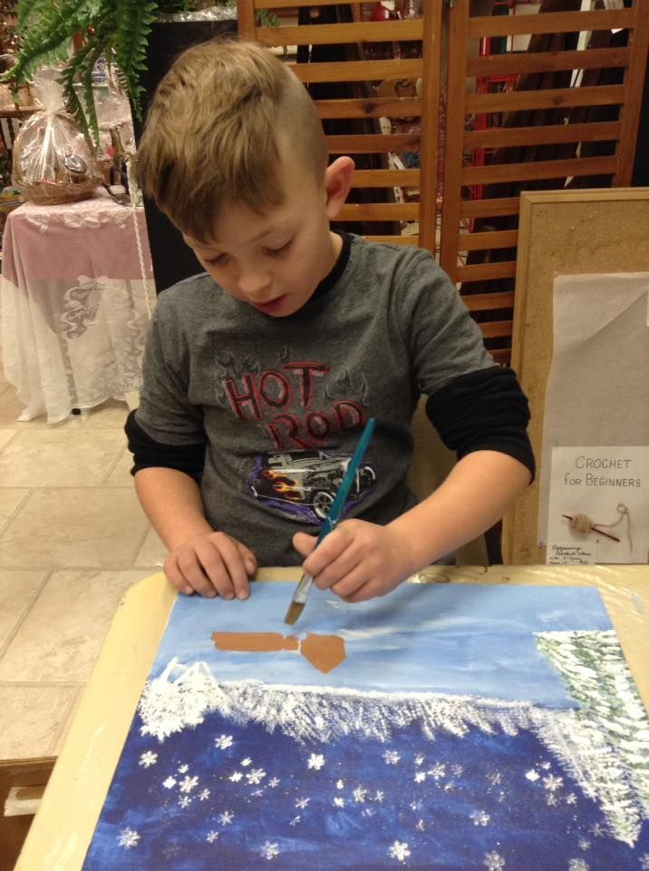 A young boy wearing a hot rod shirt is painting a picture