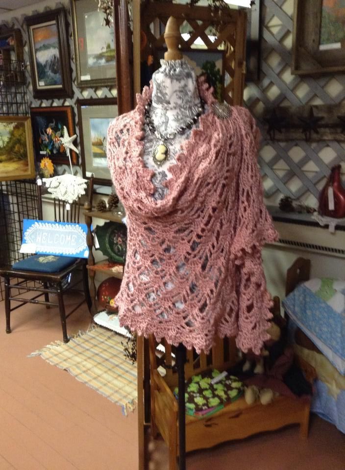 A mannequin is wearing a pink crocheted shawl
