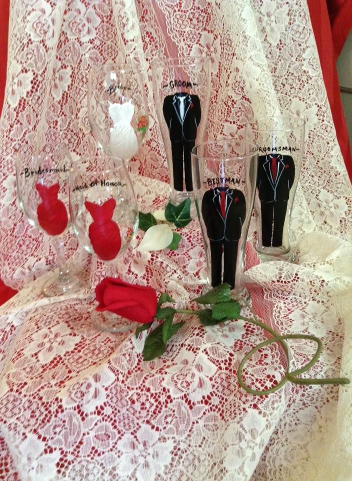 A bride and groom shot glasses are sitting on a table next to a rose.