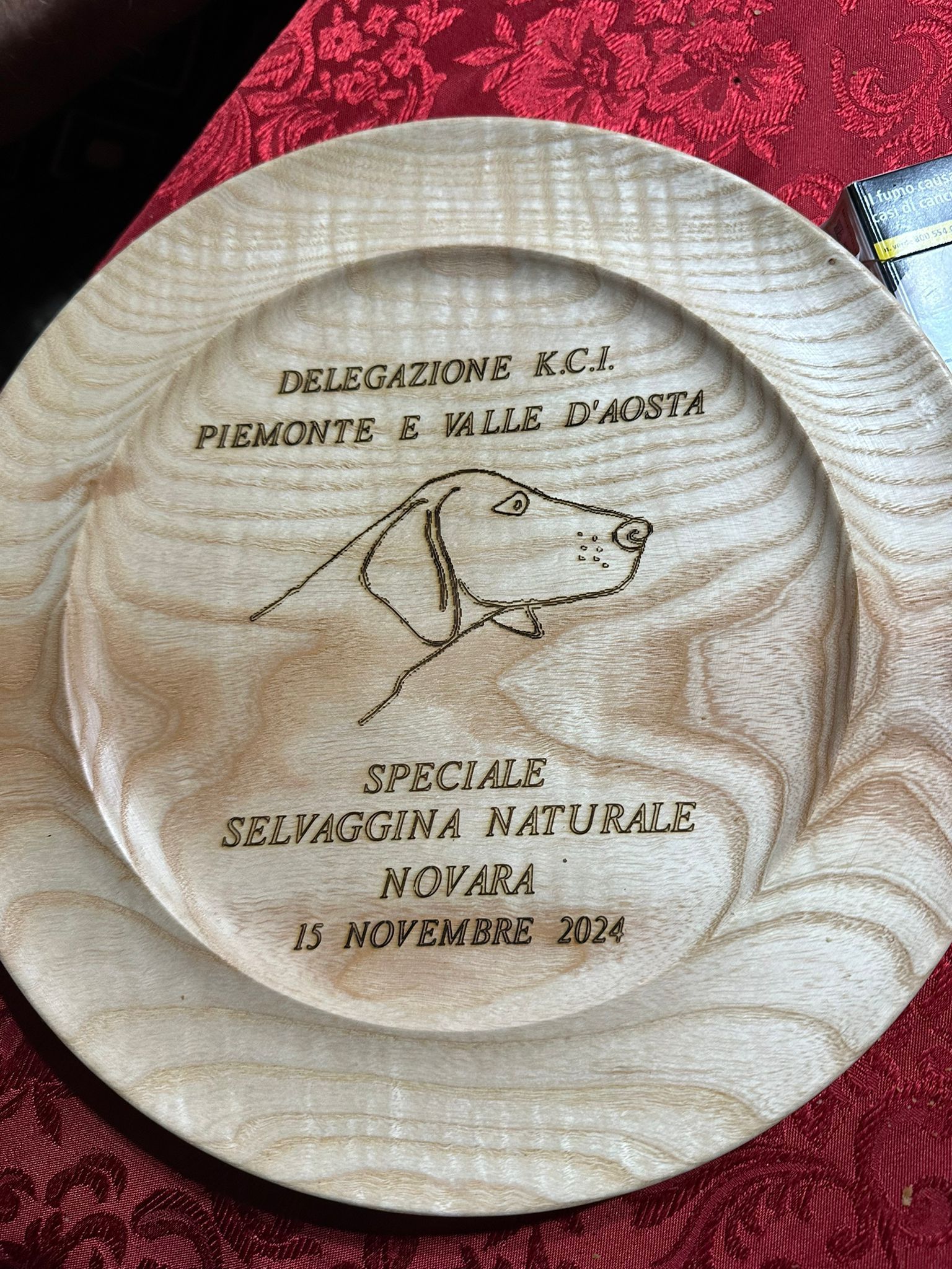 Wooden plate with engraved text and a dog outline. 
