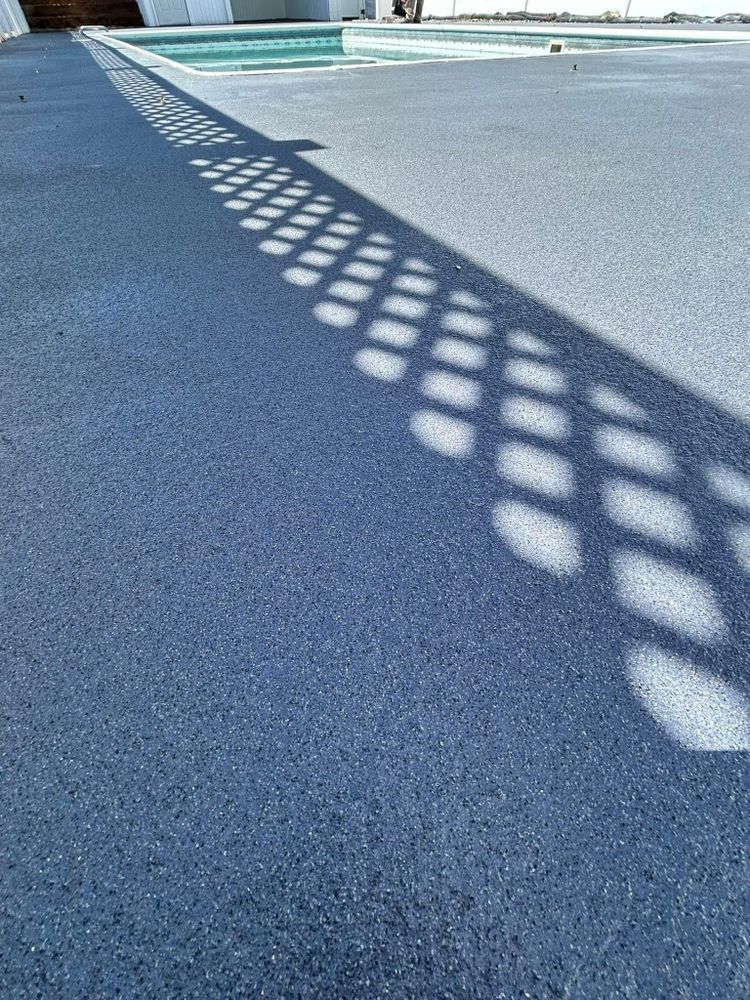 Shadow of a lattice fence on a blue-gray concrete surface near a swimming pool.