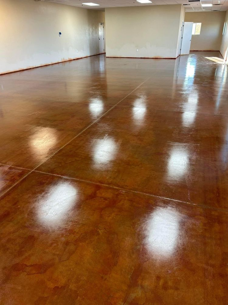 Shiny, stained concrete floor in a room with white walls and overhead lights.