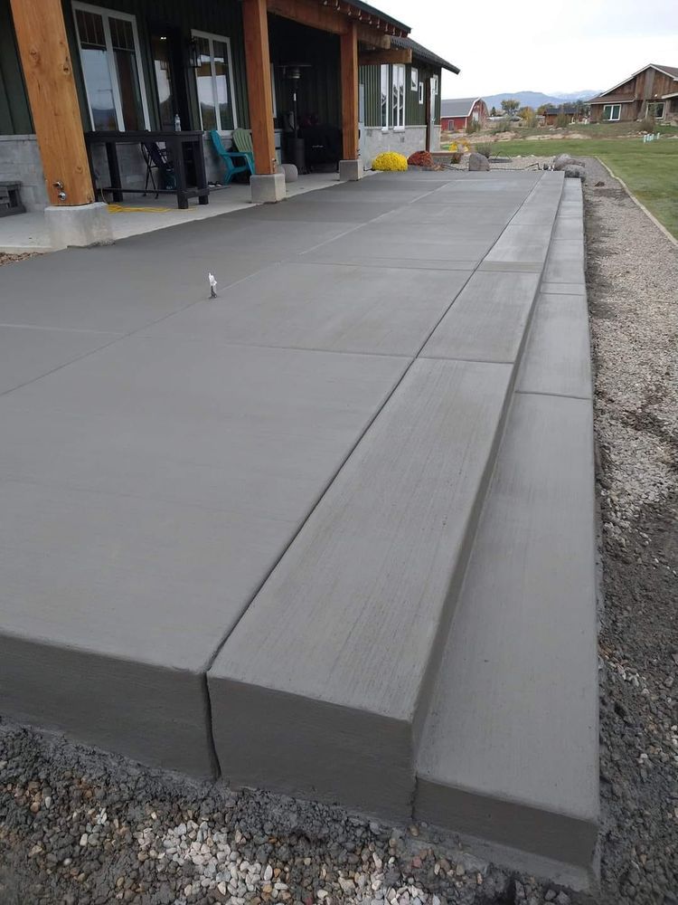 Newly poured concrete patio with steps leading down to a gravel path.