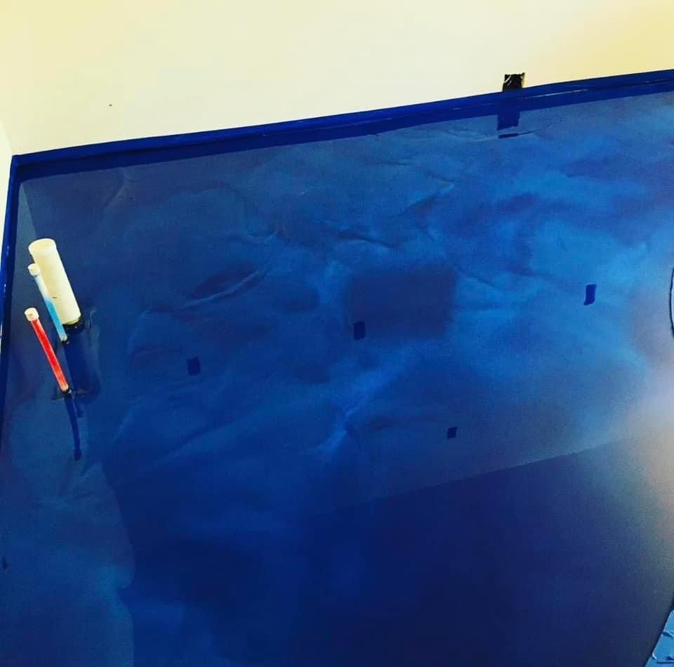 Blue metallic epoxy wall with painter's tape; tools on left.