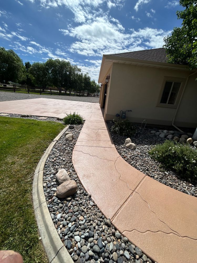Curving orange concrete walkway next to a tan building with rock border, under blue sky.