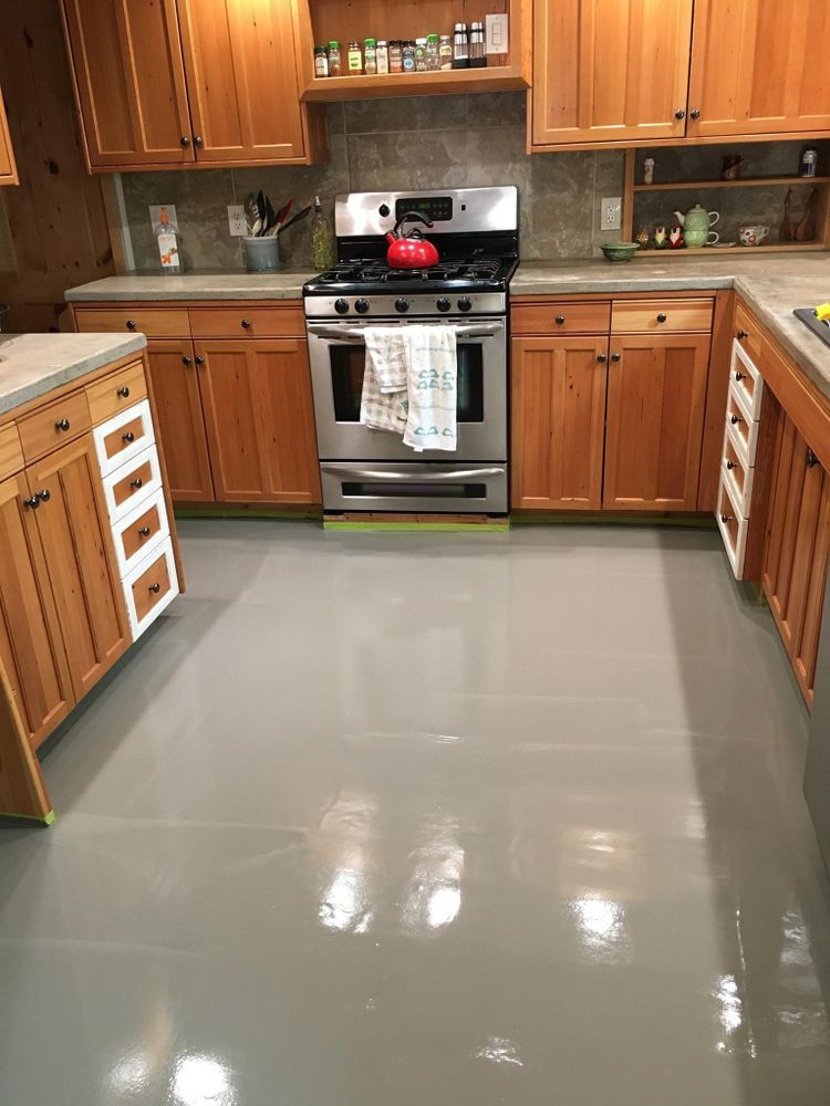 Kitchen with medium brown cabinets, stainless steel stove, and gray painted floor.