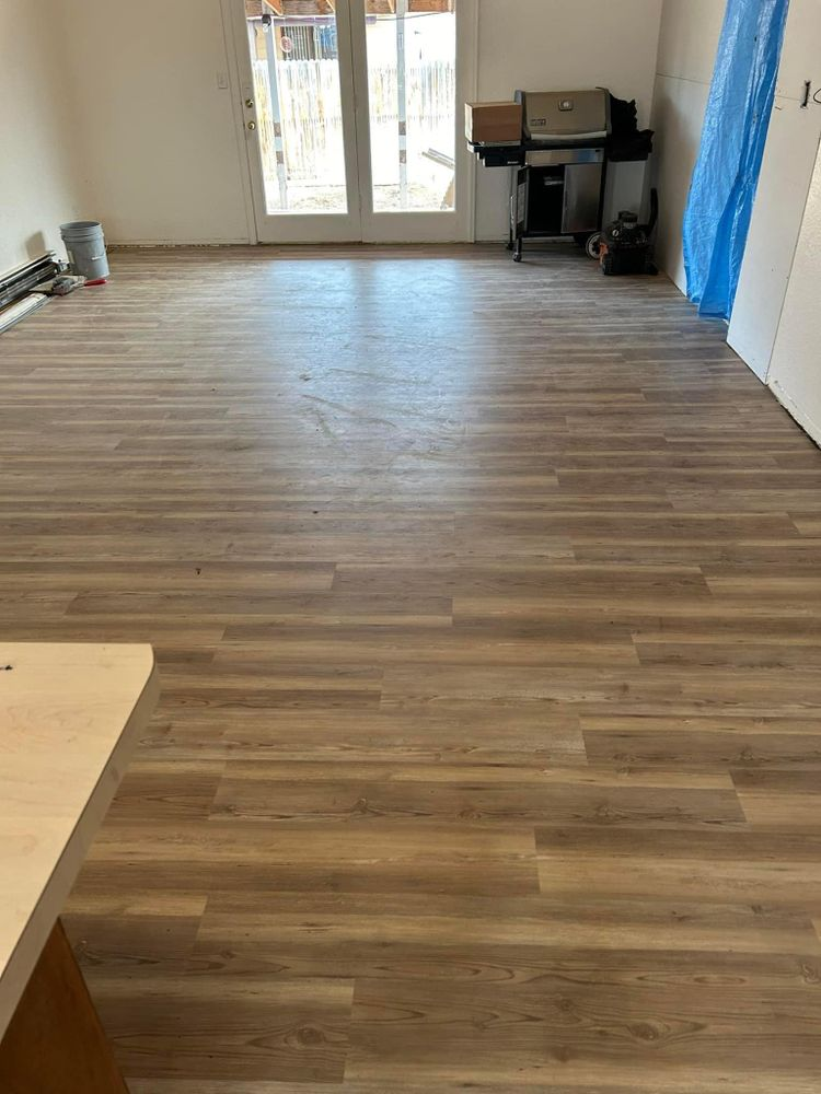 Newly installed wood-look flooring in a room with a sliding glass door and a grill.