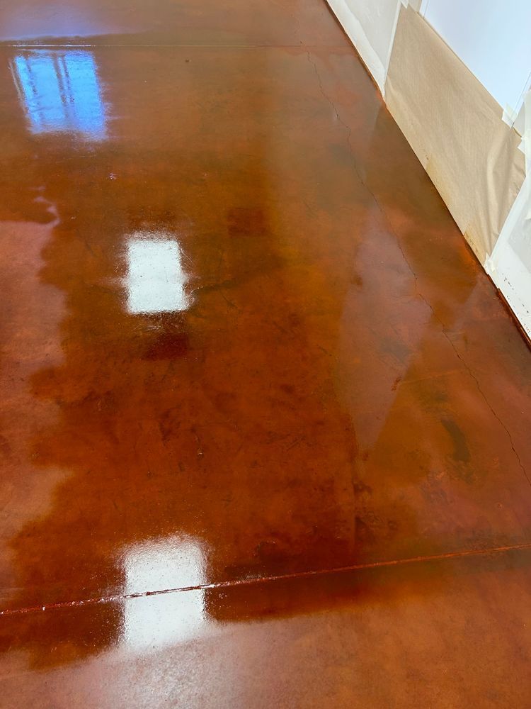 Brown, glossy epoxy floor reflecting light from windows and a white wall.