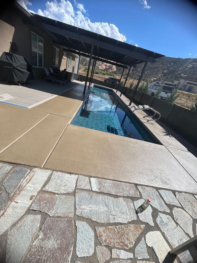 Outdoor lap pool with a dark-colored canopy, surrounded by stone and concrete patio.