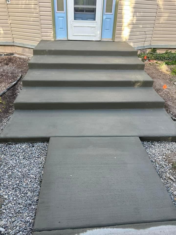 Newly poured concrete steps and walkway leading to a house entrance.