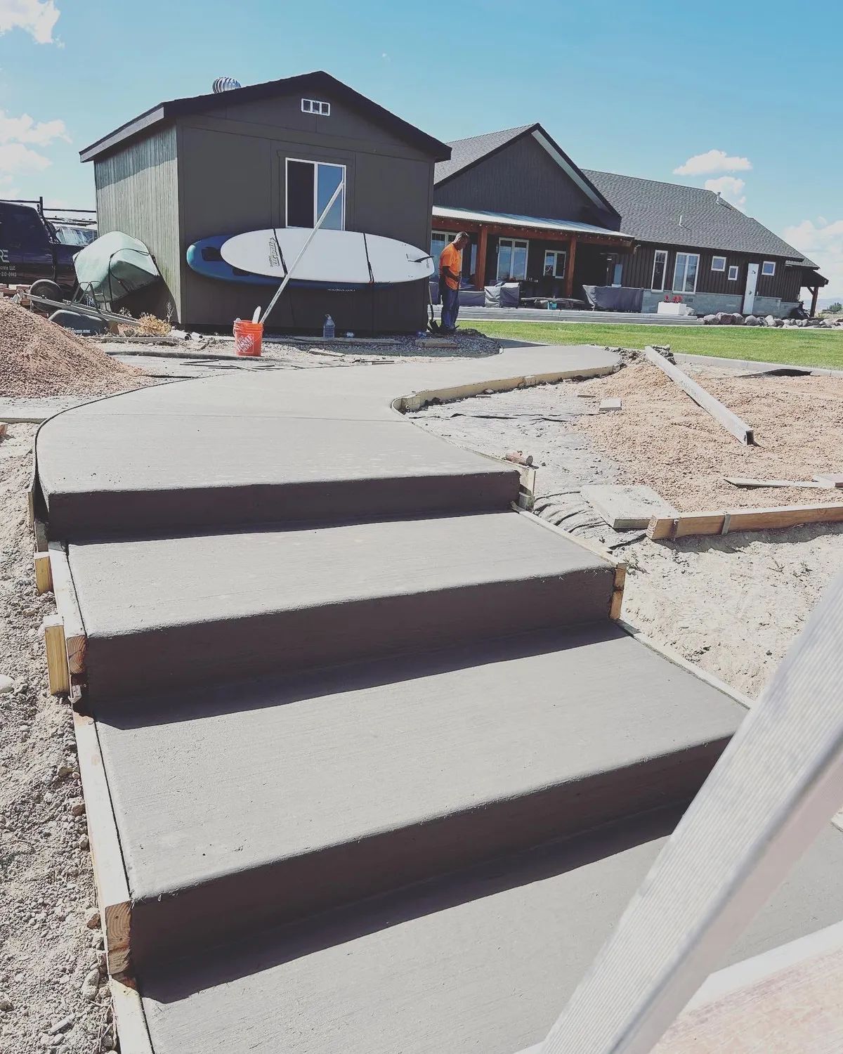 Concrete steps leading to a house with an attached shed and a person.