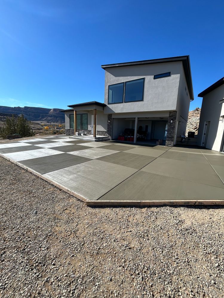 New concrete patio in front of a two-story house with a blue sky overhead.