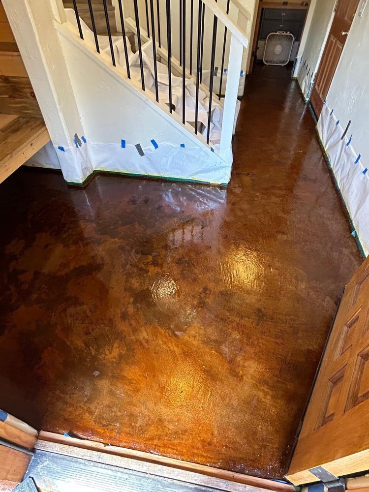 Metallic bronze epoxy flooring in a home entryway. Staircase and door frame visible.