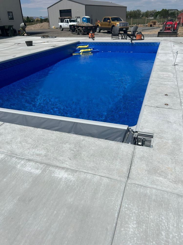 Pool with blue water and concrete surround under construction.