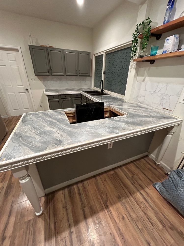 Kitchen with gray cabinets, a large island with a cooktop cutout, and wood floors.