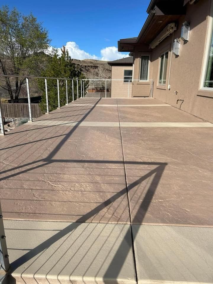 Brown deck with metal railing next to a tan building on a sunny day.