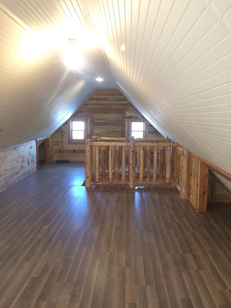 Wooden attic room with sloped ceiling, wood floors, and small windows.