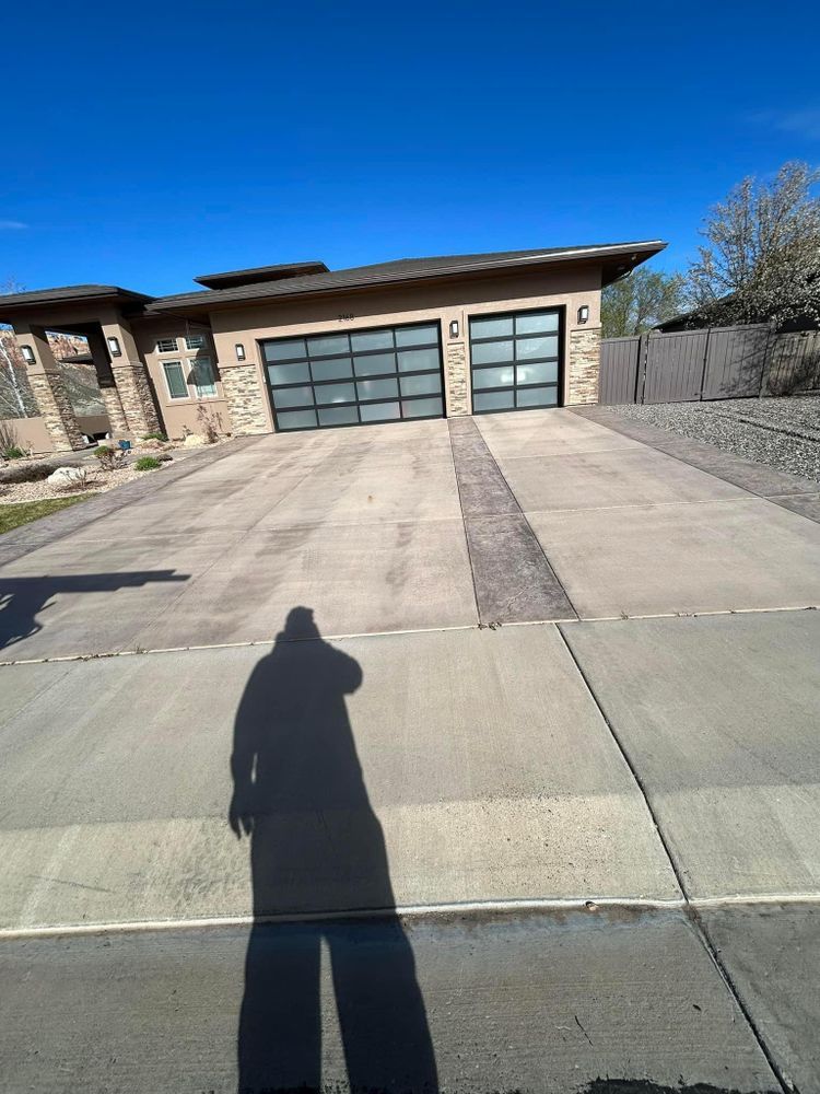 Shadow of person on concrete driveway in front of a modern home with glass garage doors.