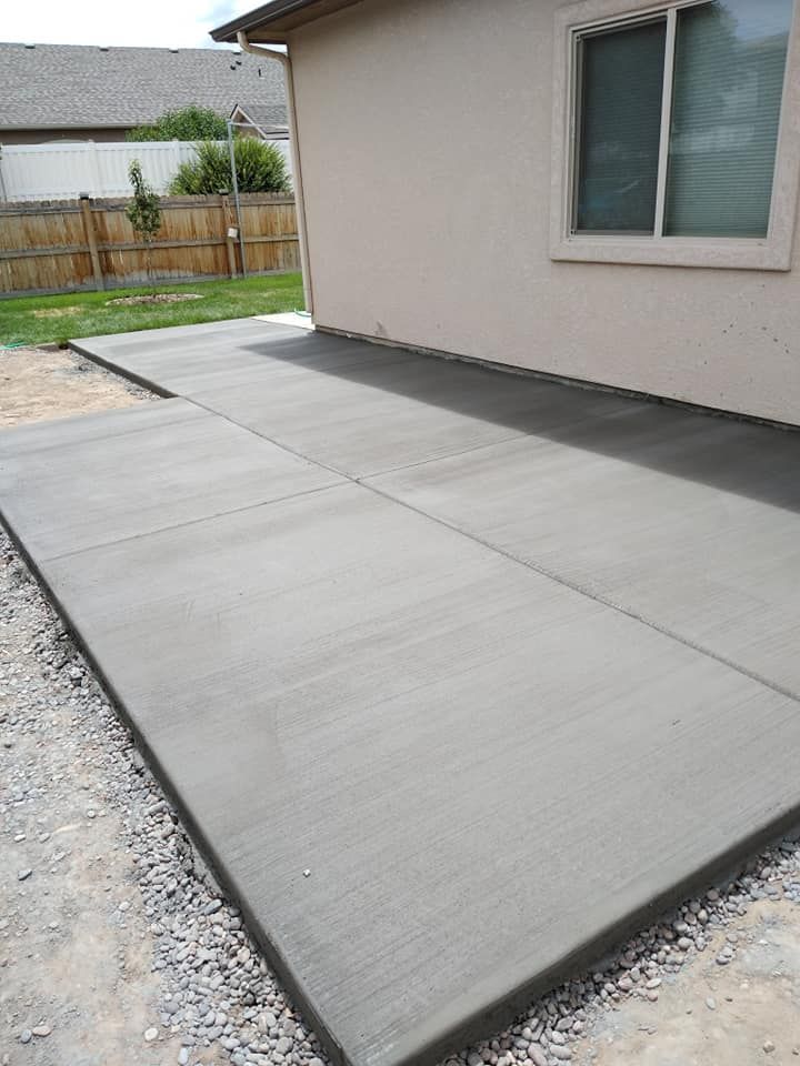 Newly poured concrete patio next to a house with a window. 