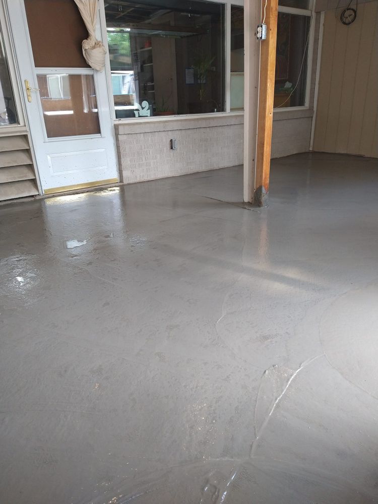 Gray concrete floor in a room with a white door, large windows, and a wooden post.