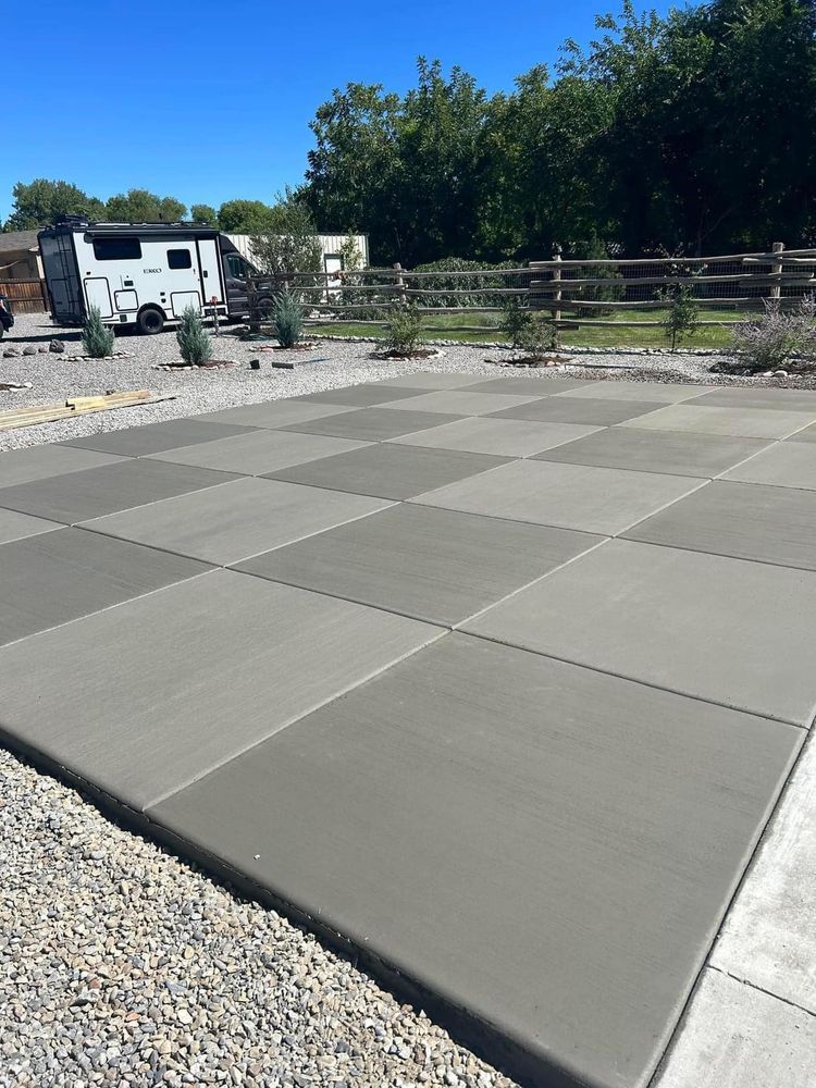 Checkered concrete patio with gravel border; RV and fence in background.