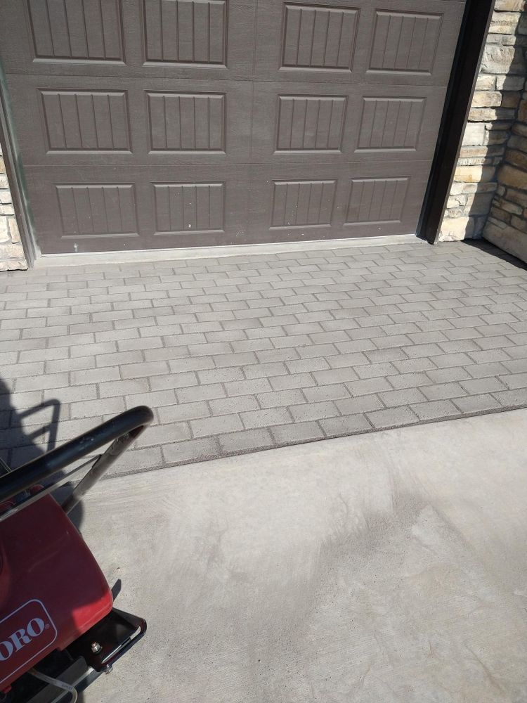 Brown garage door, gray paver driveway, concrete apron.