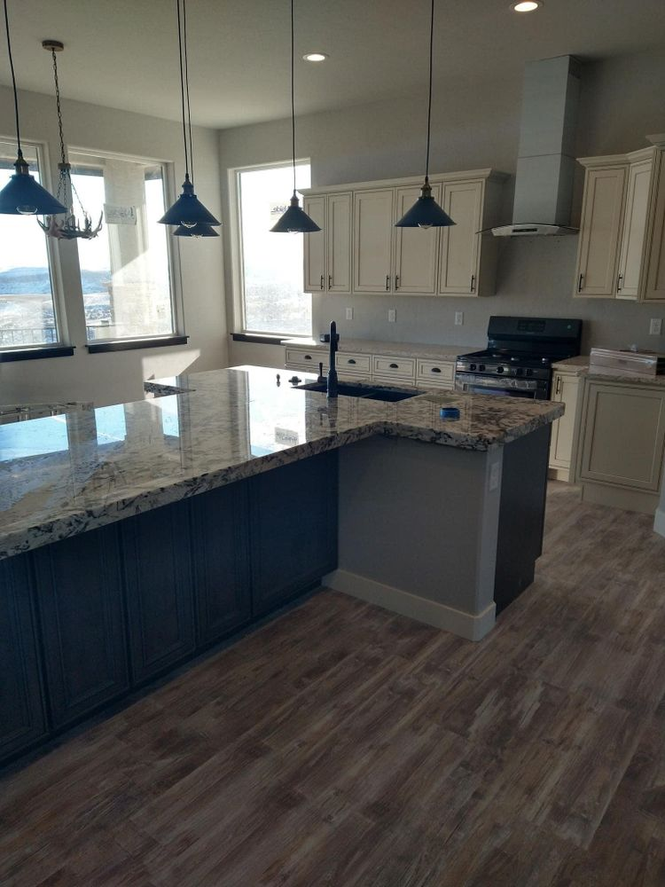 Kitchen with a large island, granite countertops, and dark blue cabinets; light cabinets on the walls.