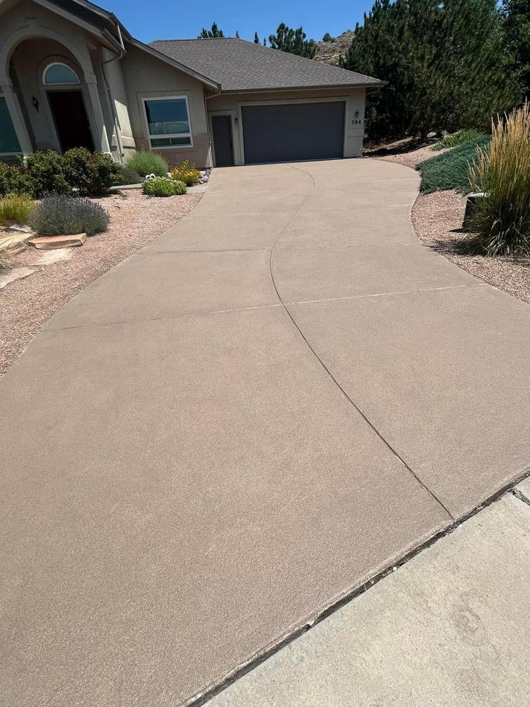 Beige concrete driveway curves toward a house with a gray garage door.