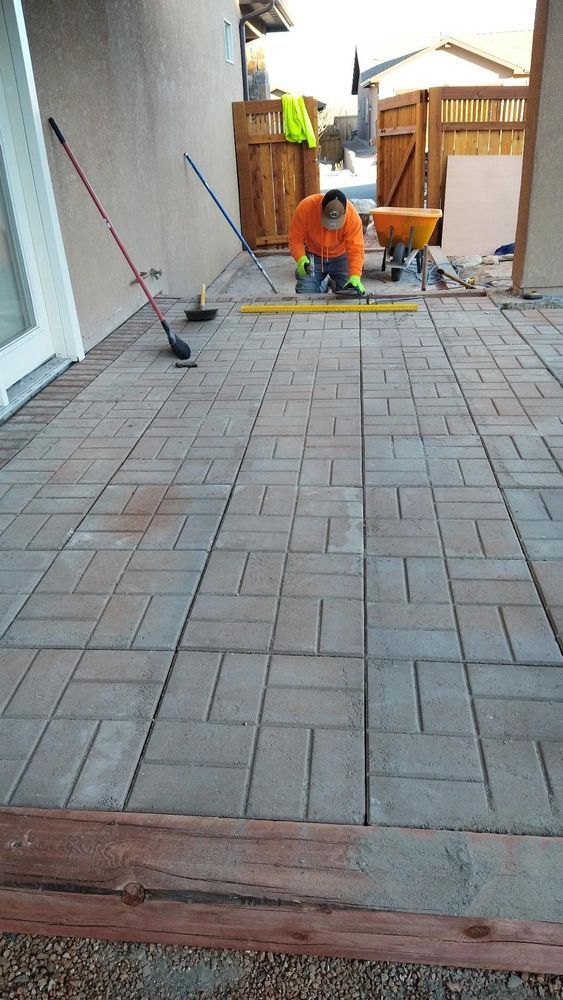 A worker cutting paving stones on a patio.