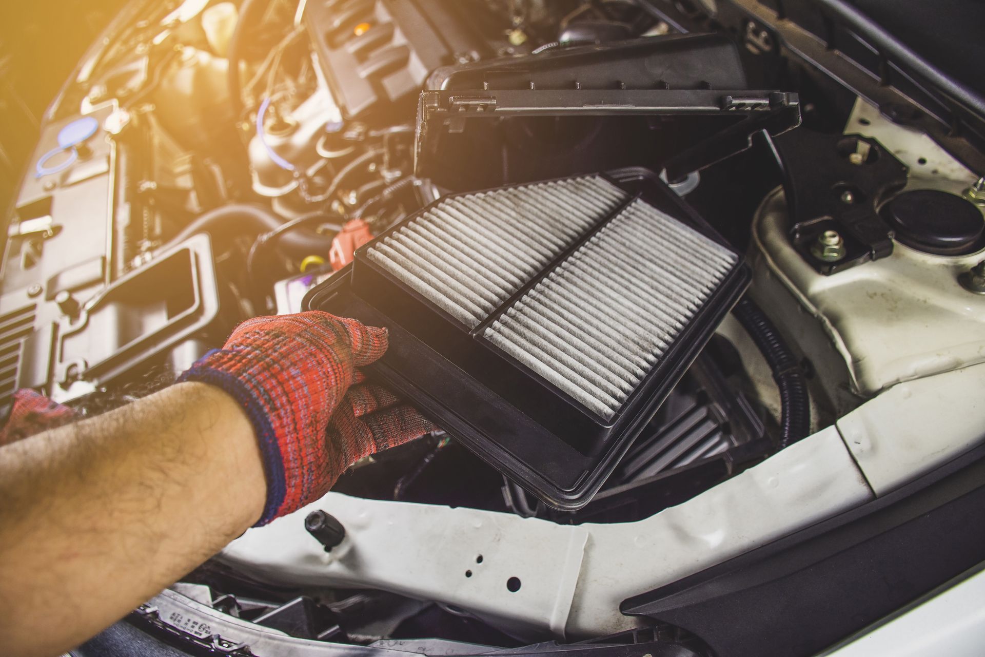 A man is changing an air filter in a car.