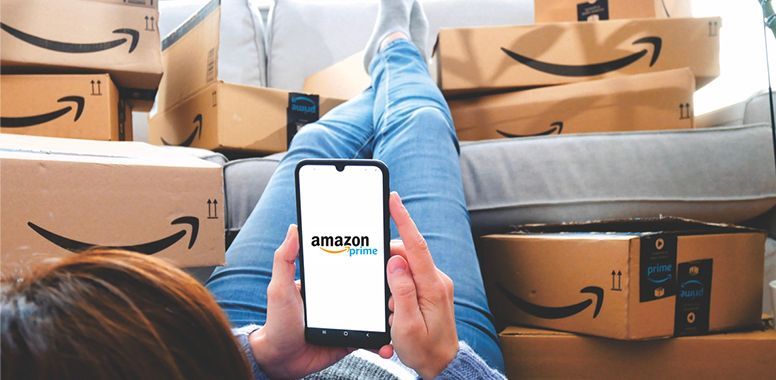 Person holding a phone with the Amazon logo, surrounded by Amazon boxes.