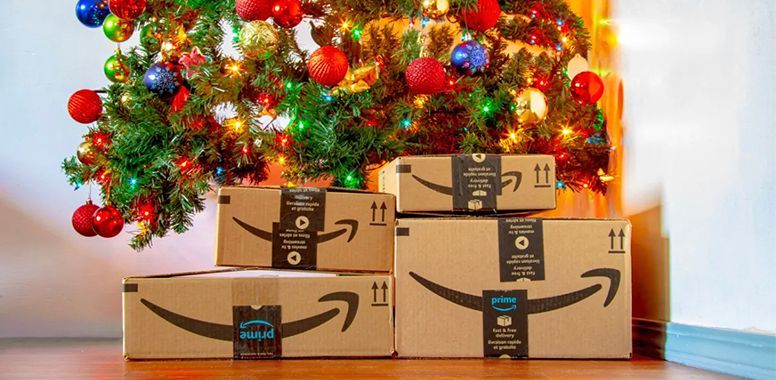 A stack of amazon boxes sitting in front of a christmas tree.