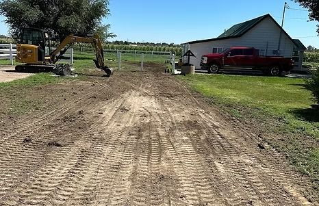 Dirt driveway with tractor, white fence, red truck, and house in sunny setting.