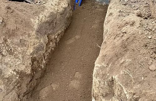 Narrow trench dug in brown soil.