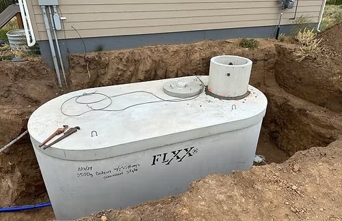 Concrete septic tank in a partially dug trench next to a building.