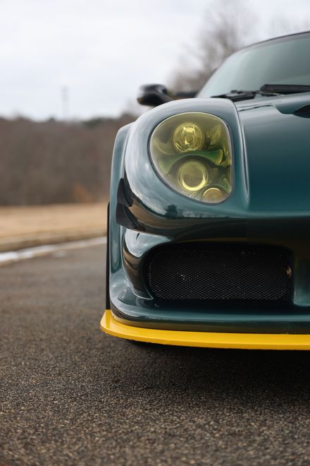 A green and yellow sports car is parked on the side of the road.