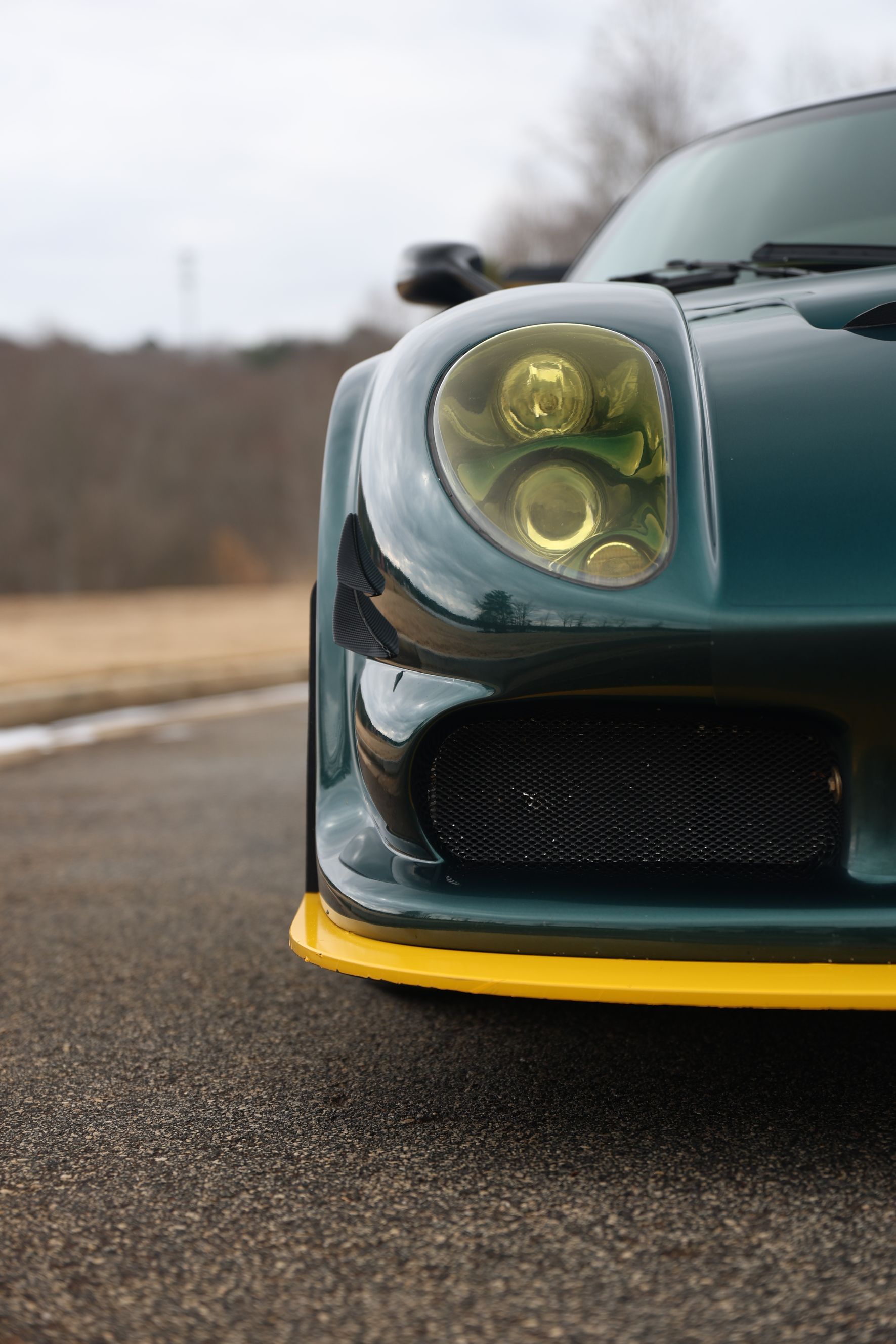 A green and yellow sports car is parked on the side of the road.