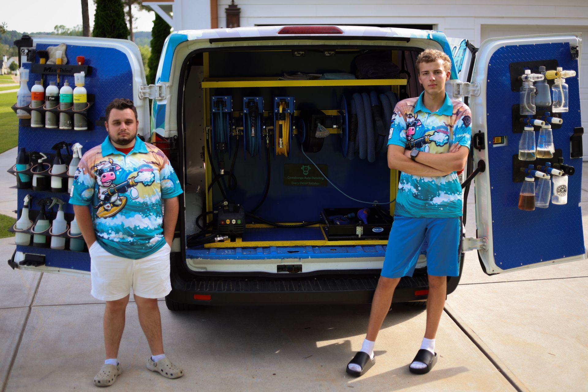 A man is kneeling down to wash a black car.