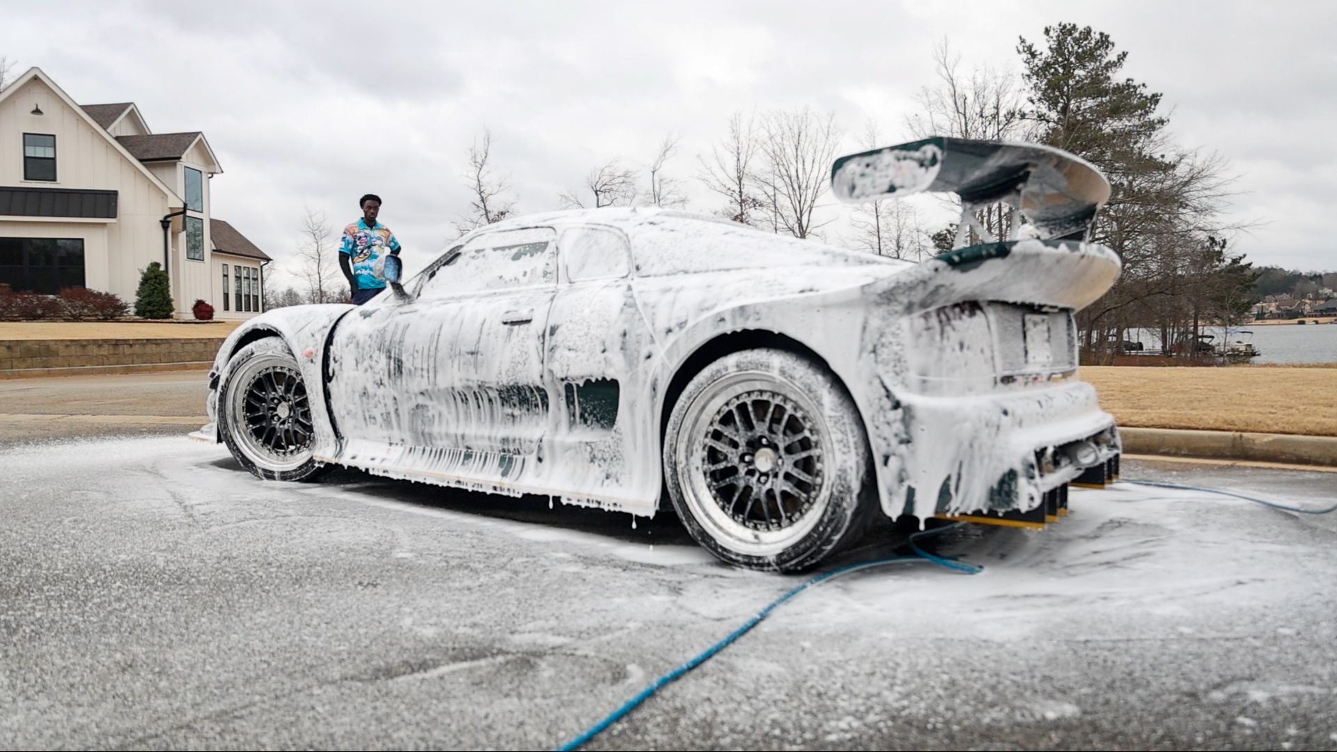 A man is washing a sports car with foam.