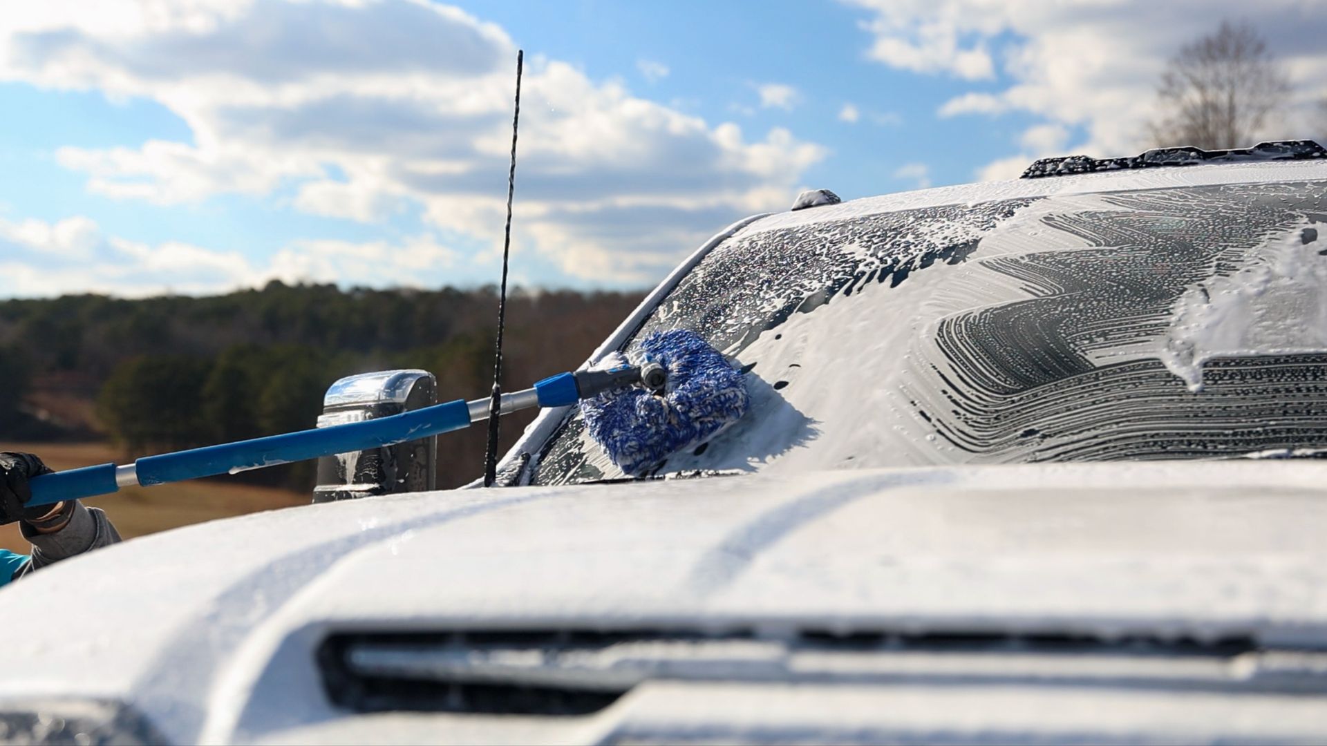 A white truck is being cleaned with a foam brush.