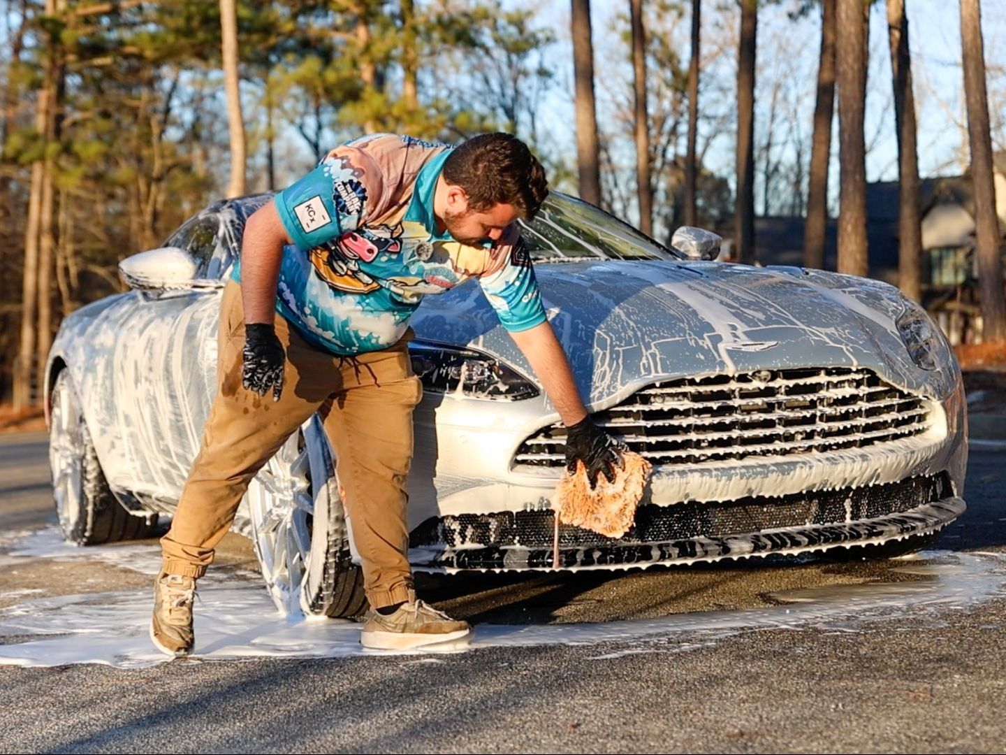 A man is washing a car with a sponge.