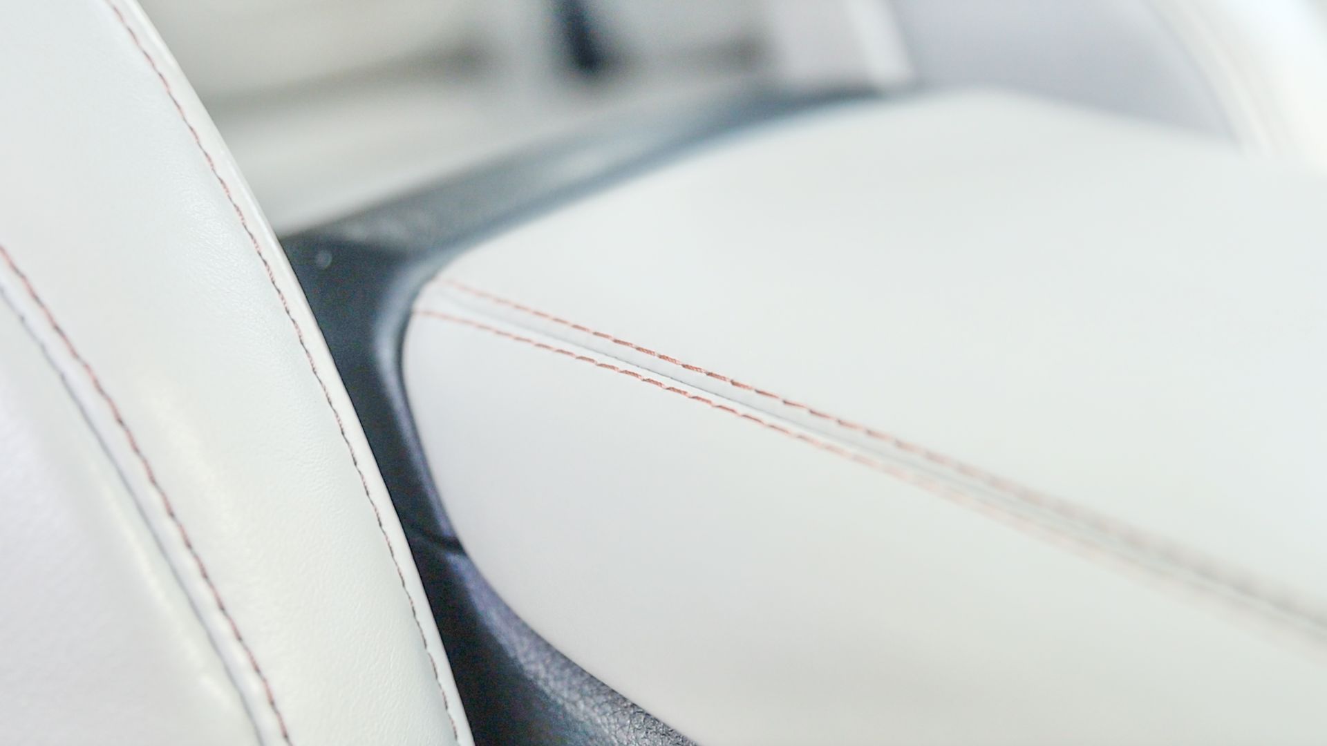 A close up of a white chair with red stitching