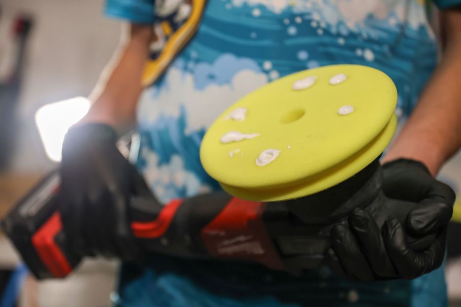 A person is holding a yellow polishing pad in their hands.