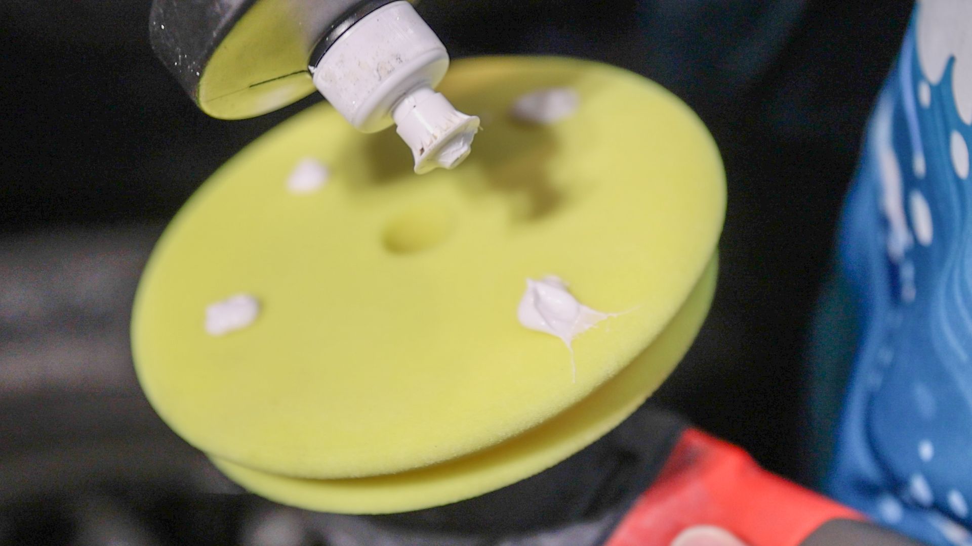 A person is polishing a yellow disc with a polisher.