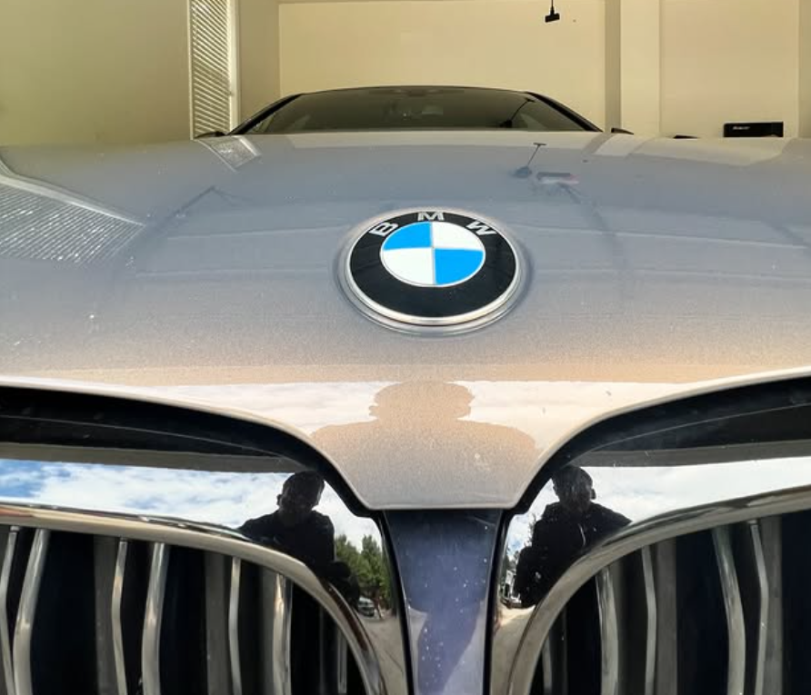 A blue bmw is parked on the side of the road.