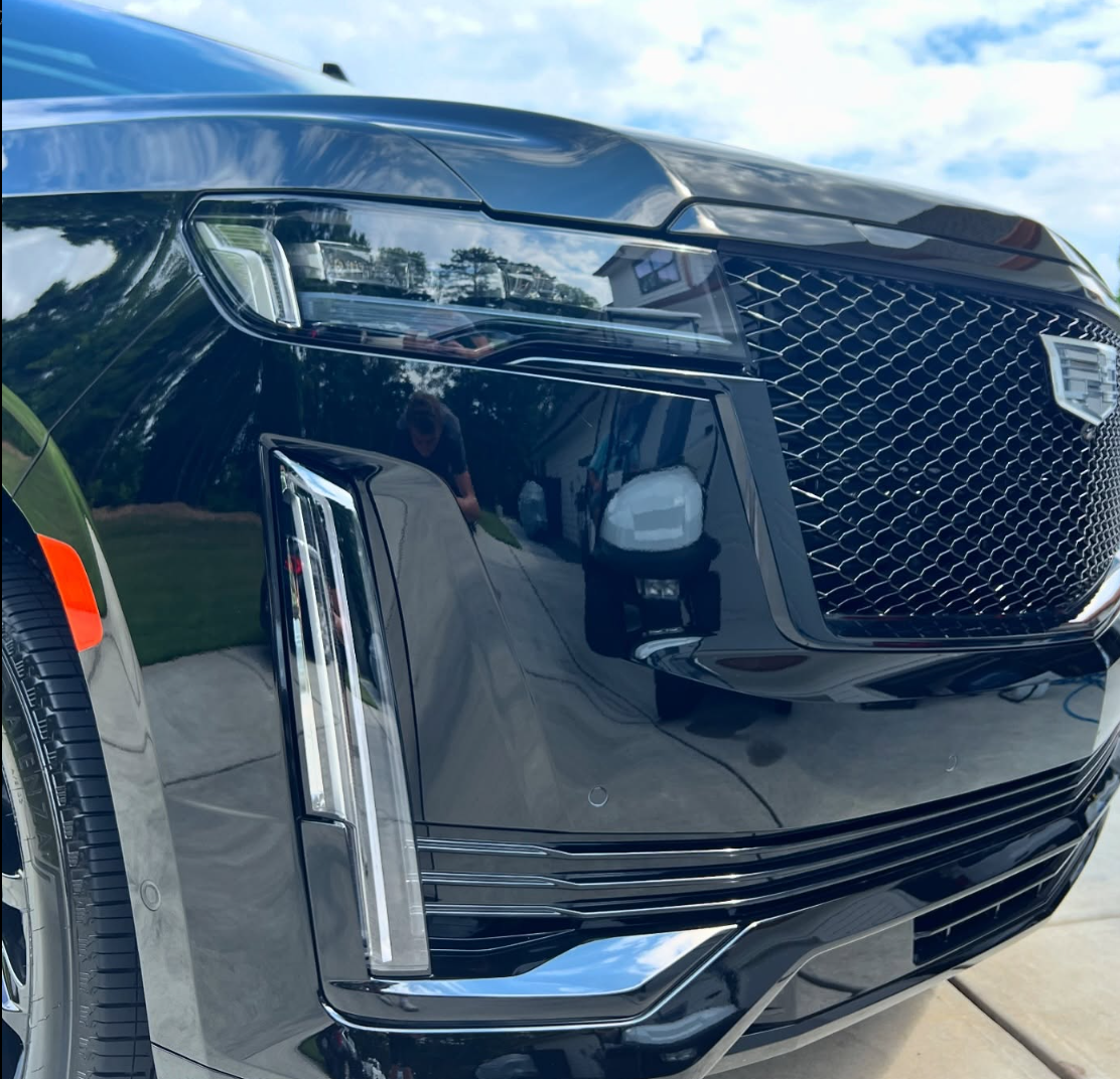 A red sports car is driving down a road in the woods.