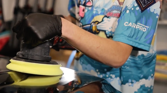 A person is polishing a car with a machine.