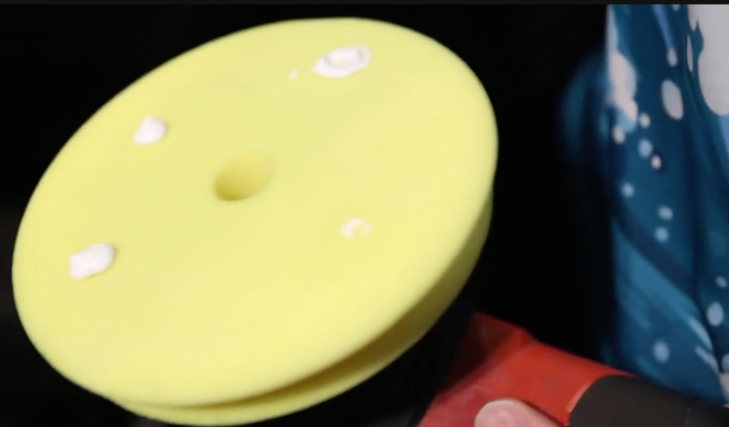 A yellow sponge is being used to polish a car